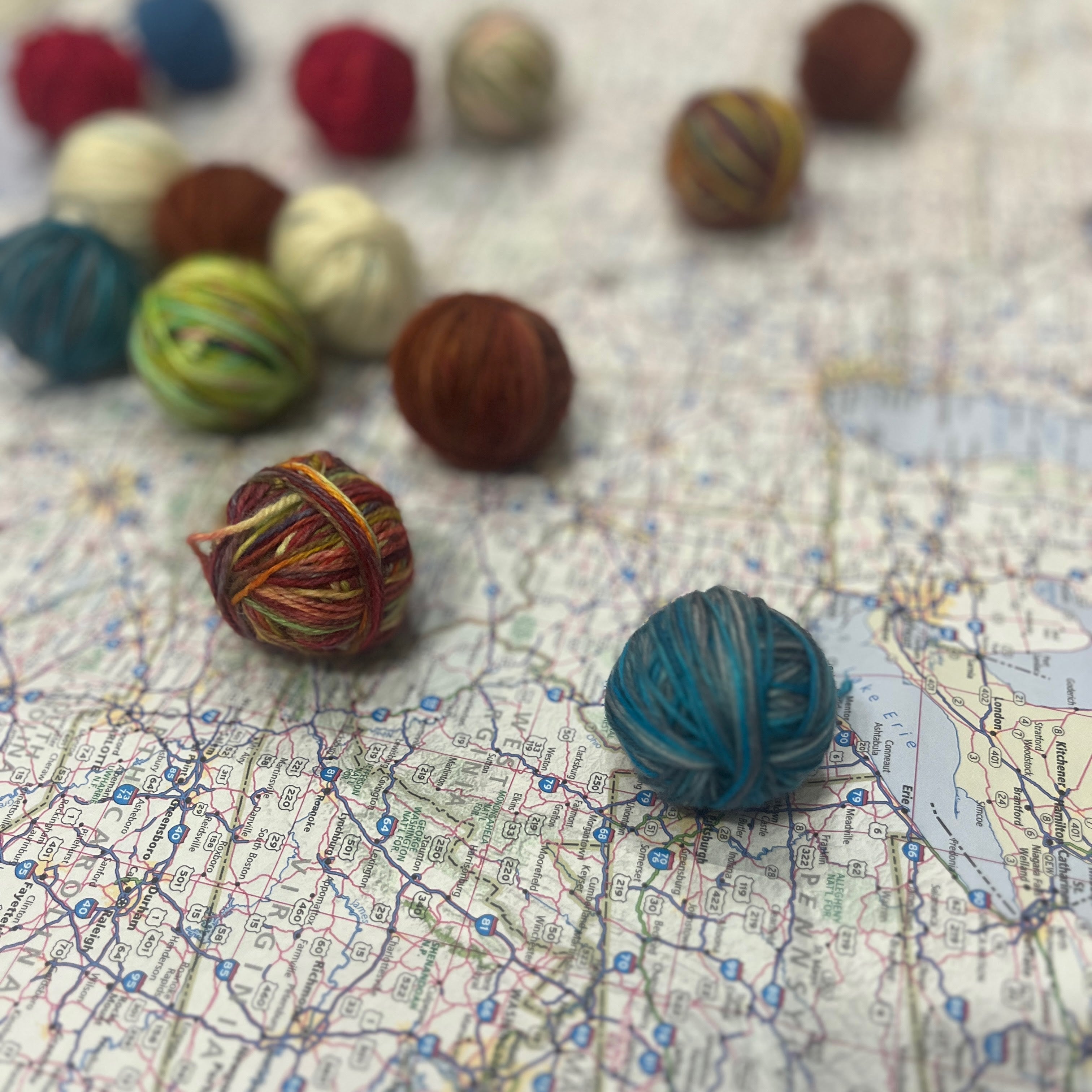 small multicolored balls of yarn roll across a highway map of the United States.