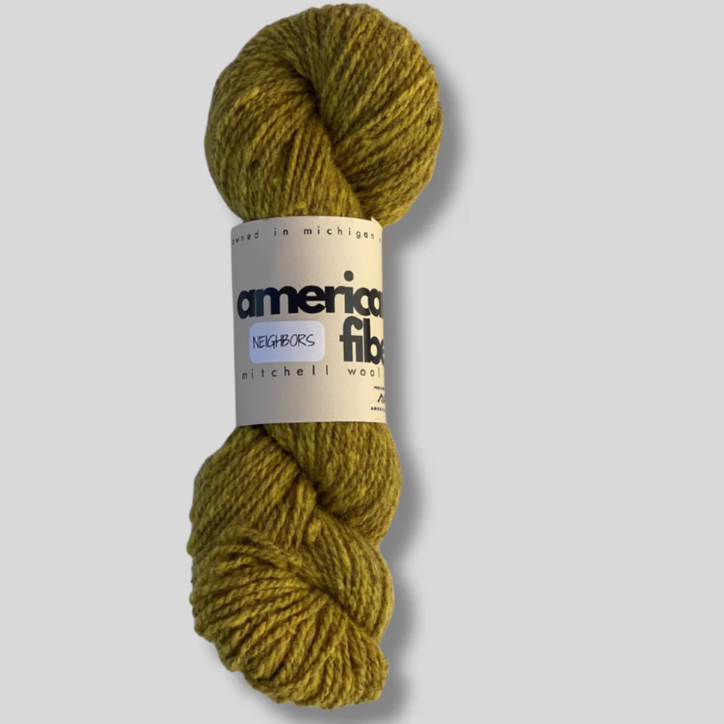 Skein of green yarn with an American Fibers label on a light gray background