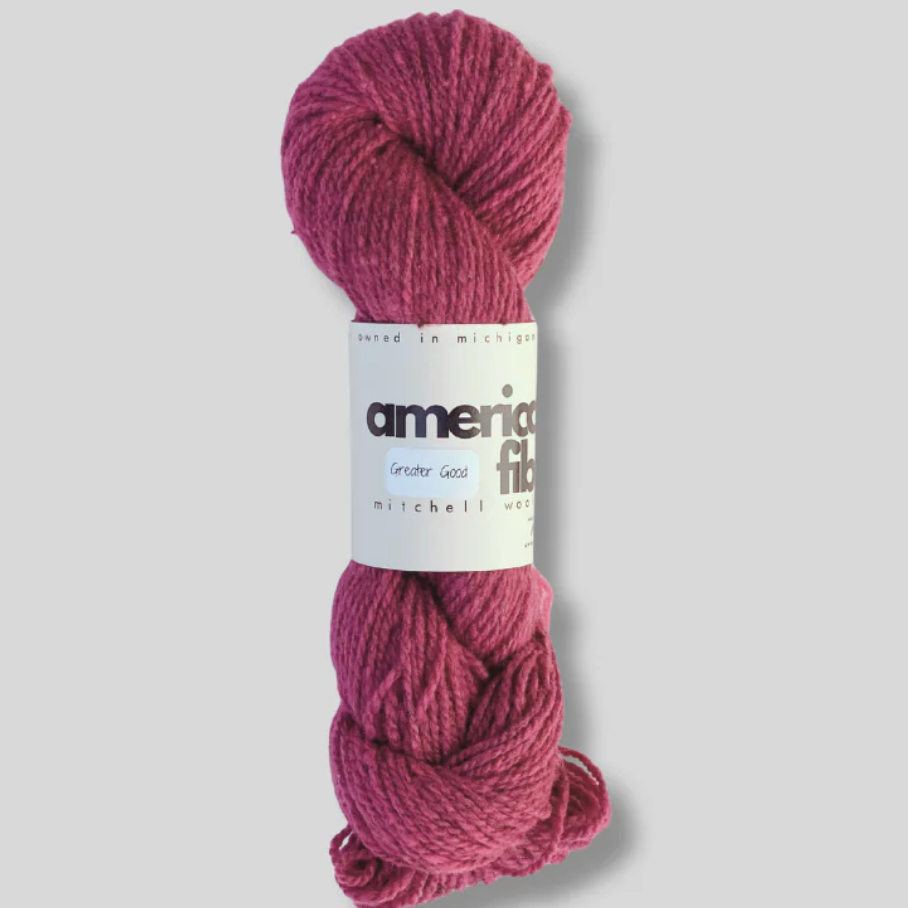 Skein of pink yarn with a label on a gray background