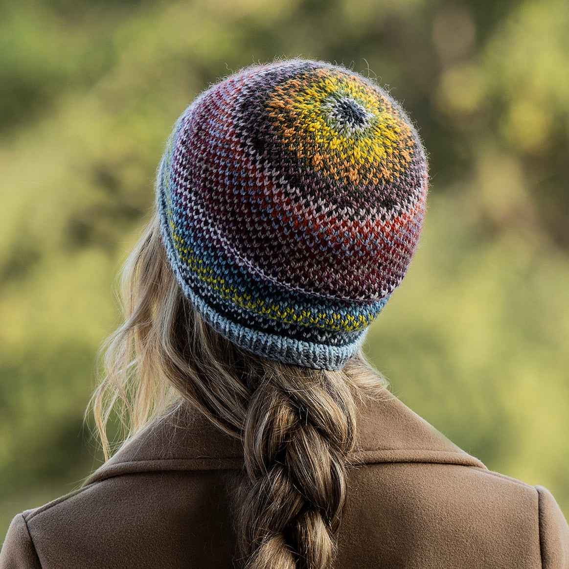 the back of a person with a braid, wearing a striped beanie.