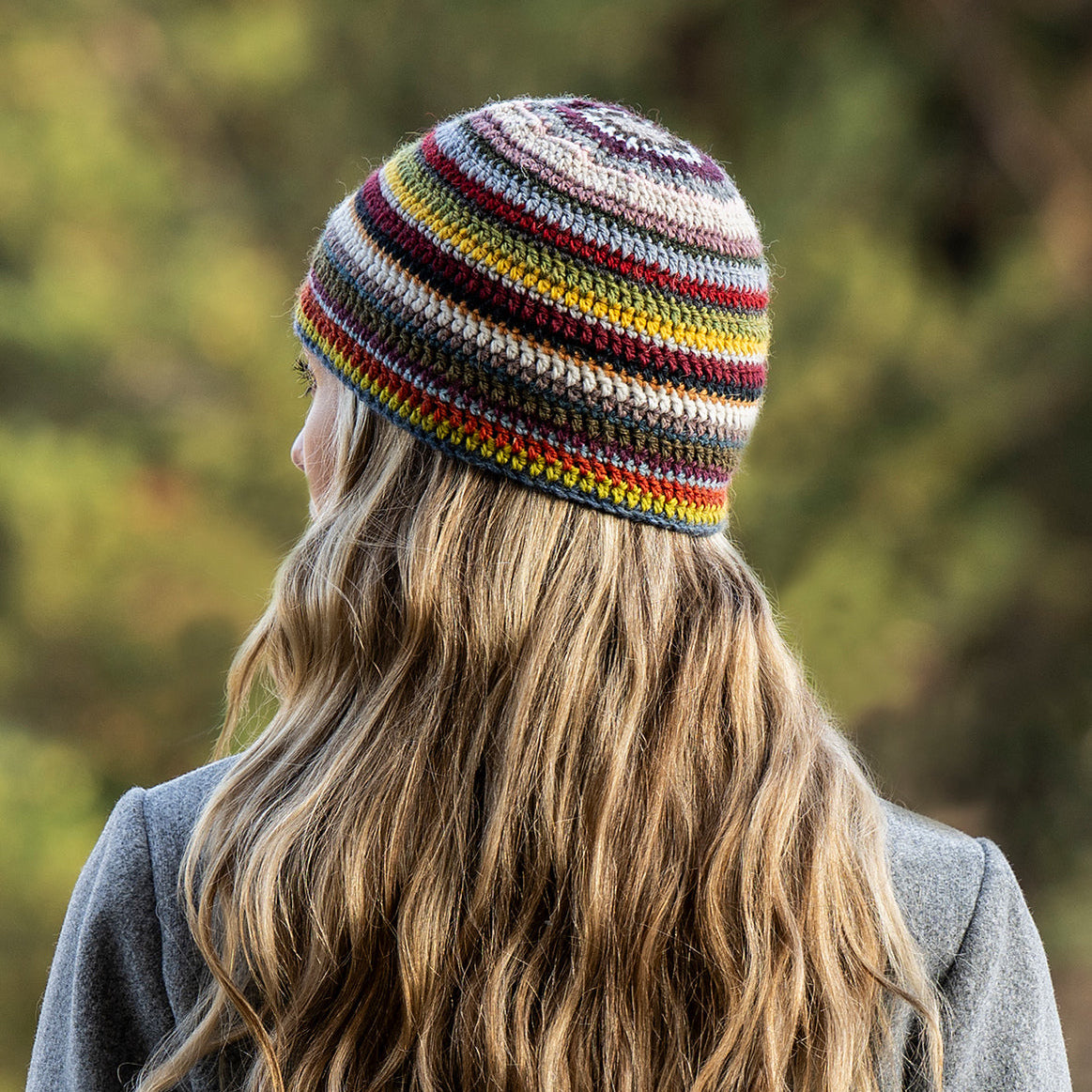Person wearing a colorful striped beanie with a blurred natural background