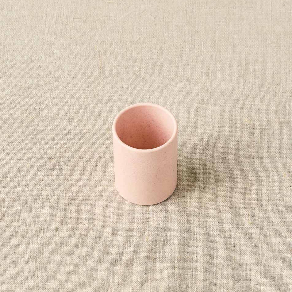 Pink ceramic cup on a beige textured surface
