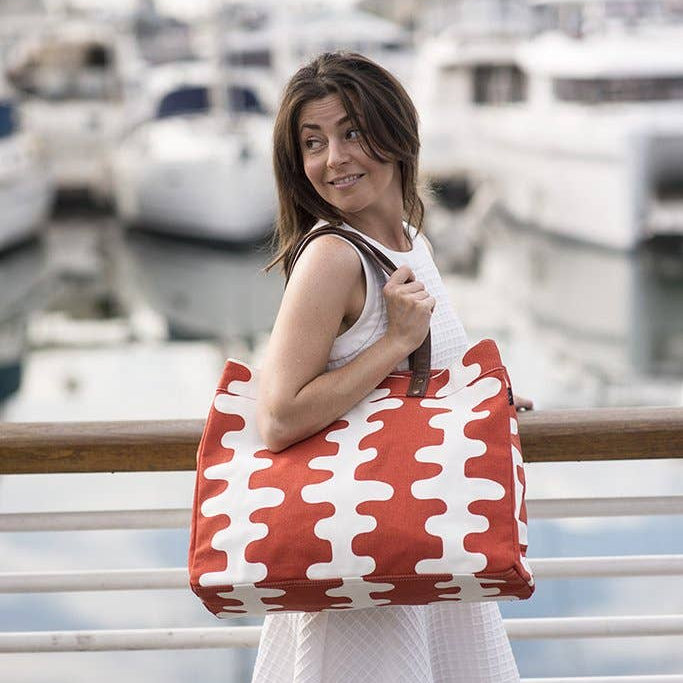 Woman holding a red and white patterned bag by a marina