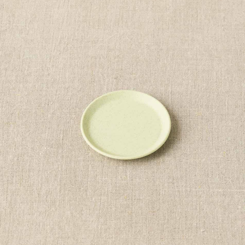 Green ceramic plate on a beige textured background