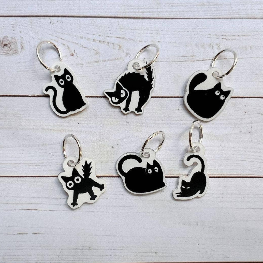 Set of black and white cat-shaped charms on a wooden surface
