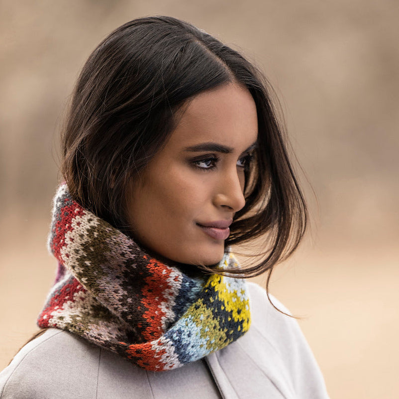 A woman pictured from the side wearing a cowl with many colors in stripes.