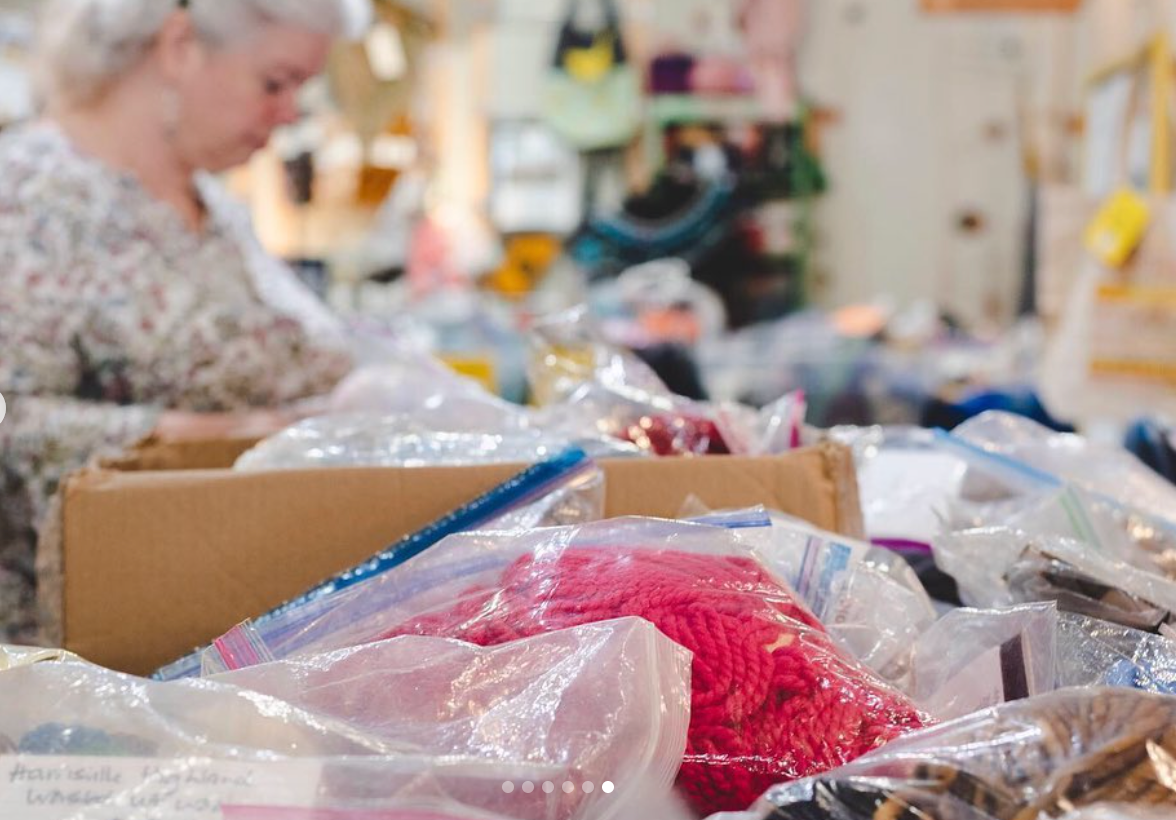 Woman searches through bin of bagged yarn.