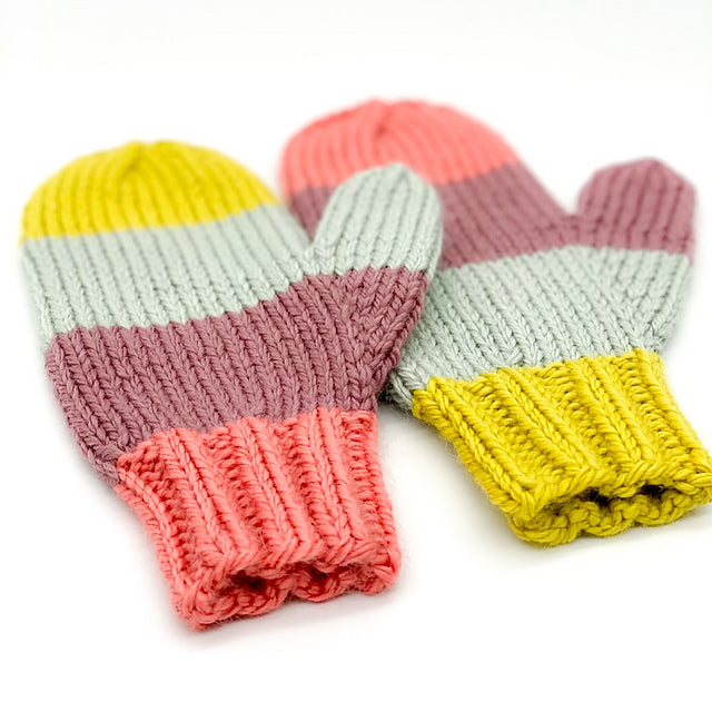 A pair of mittens in mismatched wide stripes, knit in a bulky weight yarn.