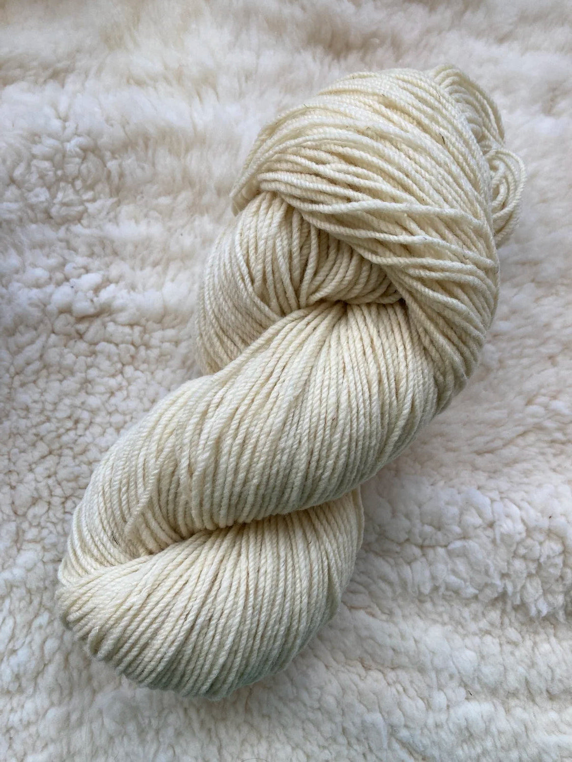 Cream skein of yarn on a textured white surface