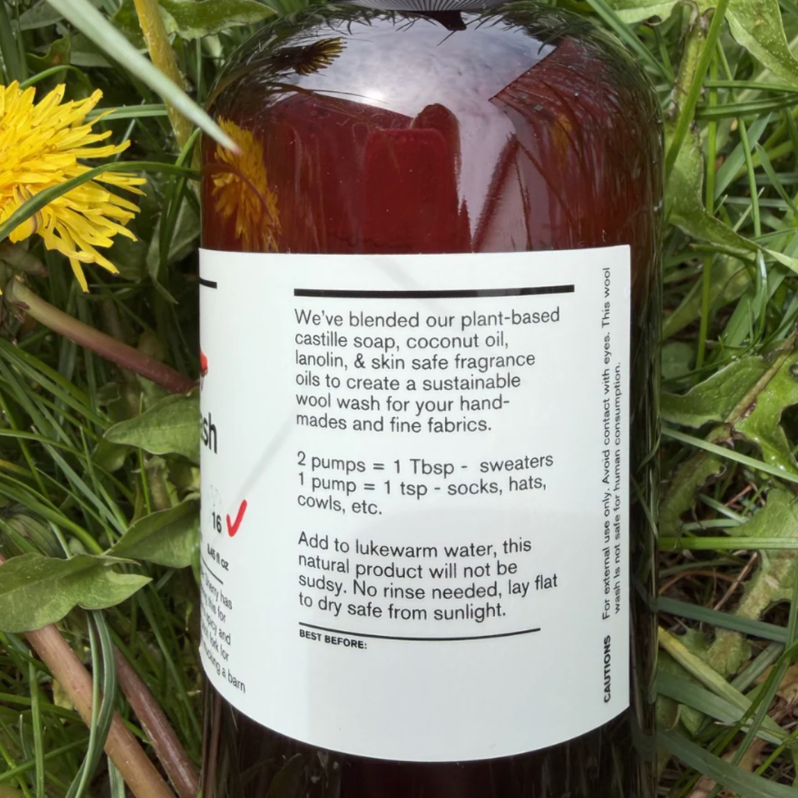 Bottle of Wool Wash with label on grass and dandelion background