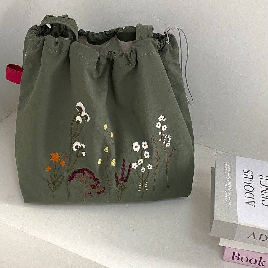 Green bag with floral embroidery on a white surface