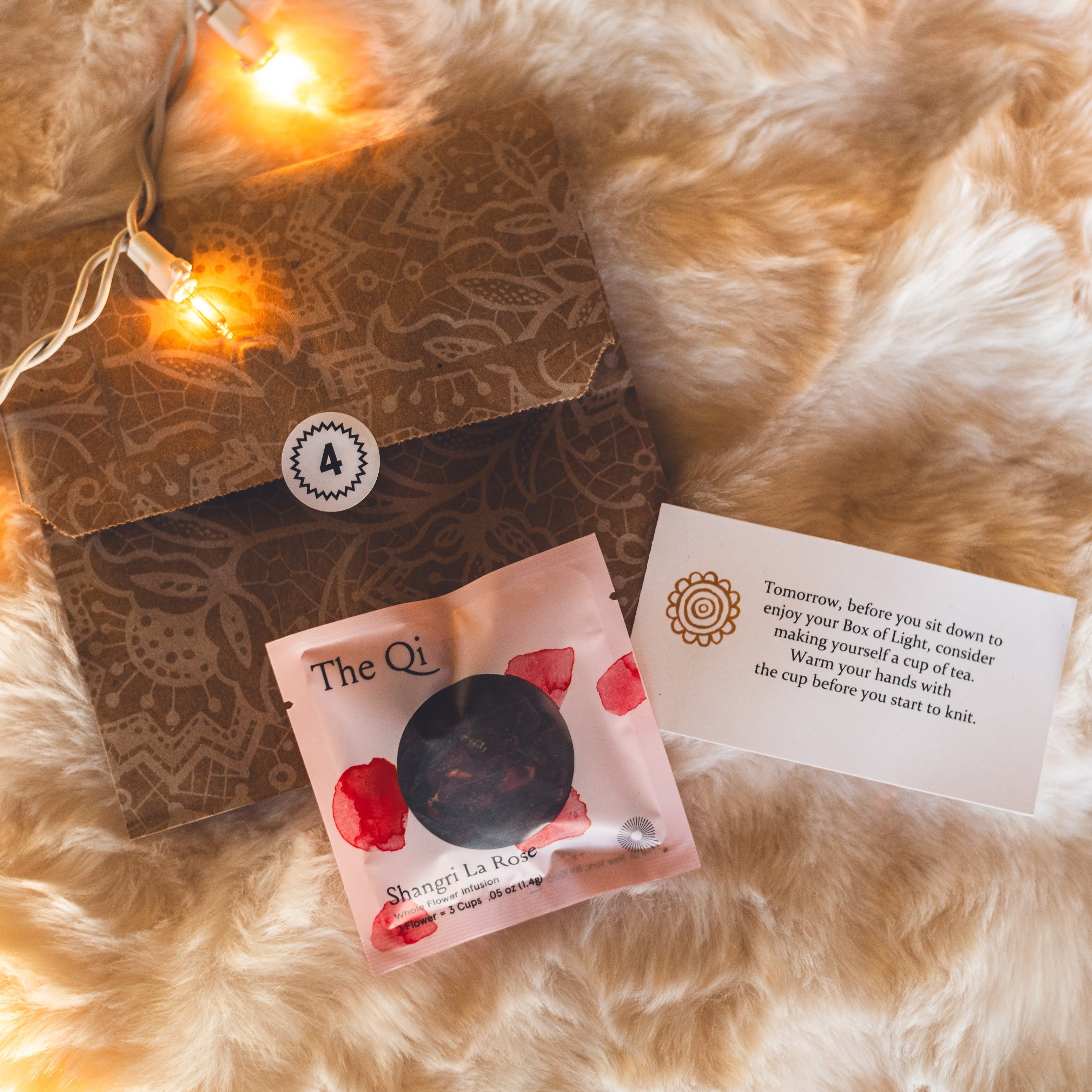 Box of Light envelope number 4 with a packet of The Qi Tea and an enclosure card that says Tomorrow, befor eyou sit down to enjoy your Box of Light, consider making yourself a cup of tea. Warm your hands with the cup before you start to knit.