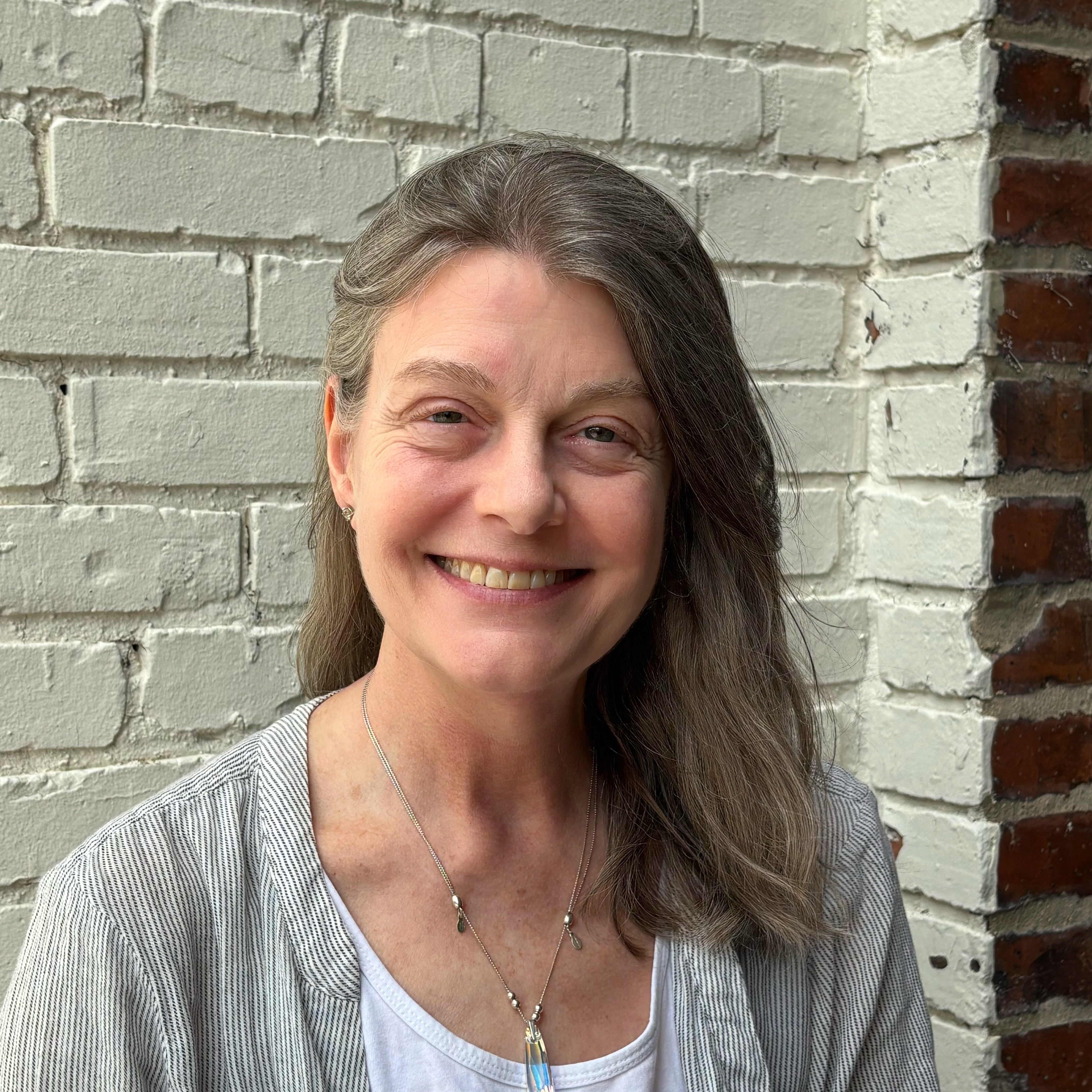 Instructor Kristen Quain smiling in front of a brick wall