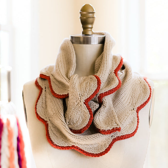 Knitted scarf with ruffled edge on a mannequin against a neutral background