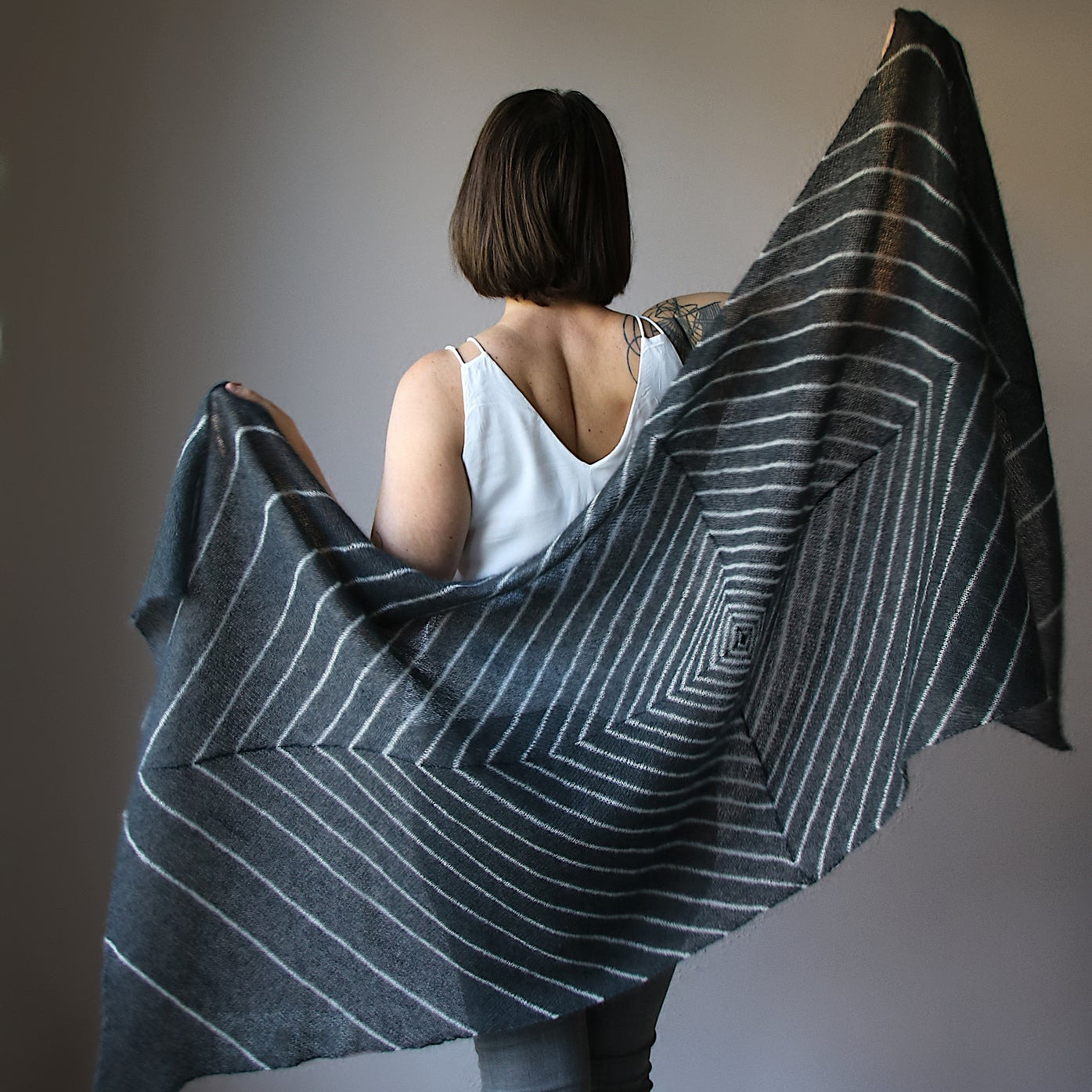 Person holding a large, patterned fabric against a plain background